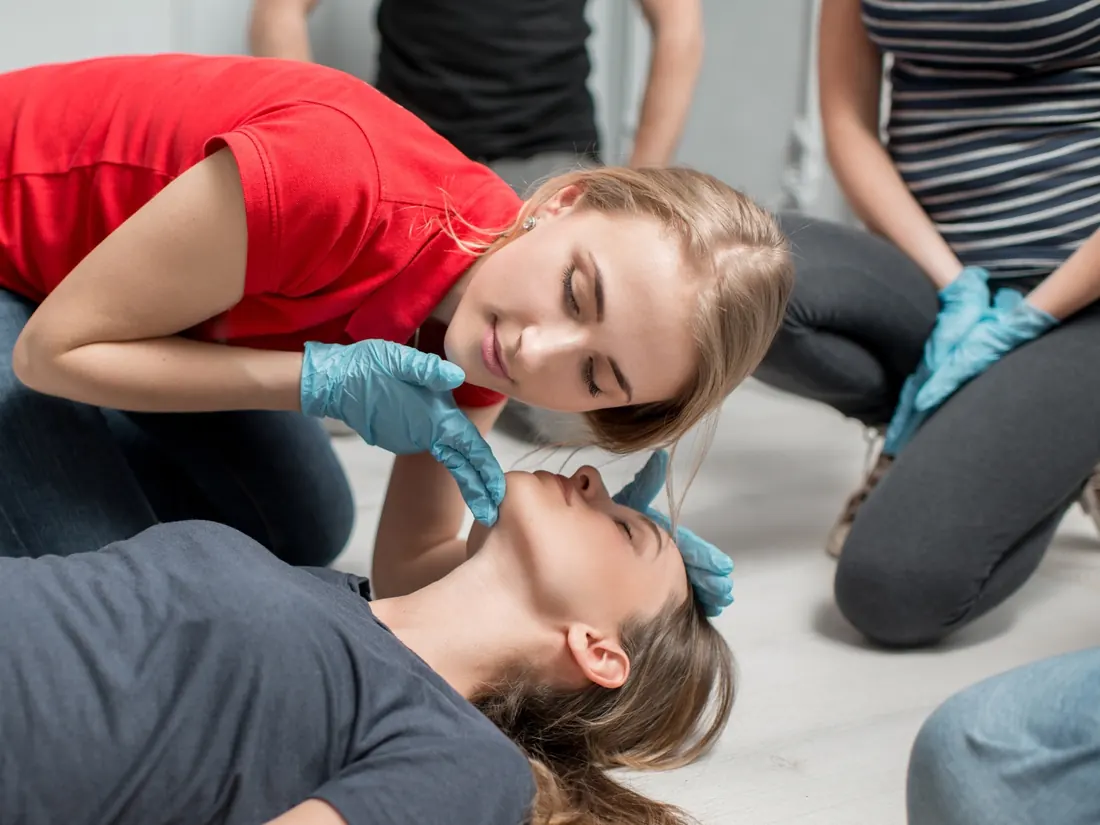 Exercice de secourisme : contrôle de la respiration d’une victime allongée